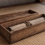 Paulownia wood kiribako box open on tatami mat with a handwritten makimono scroll inside